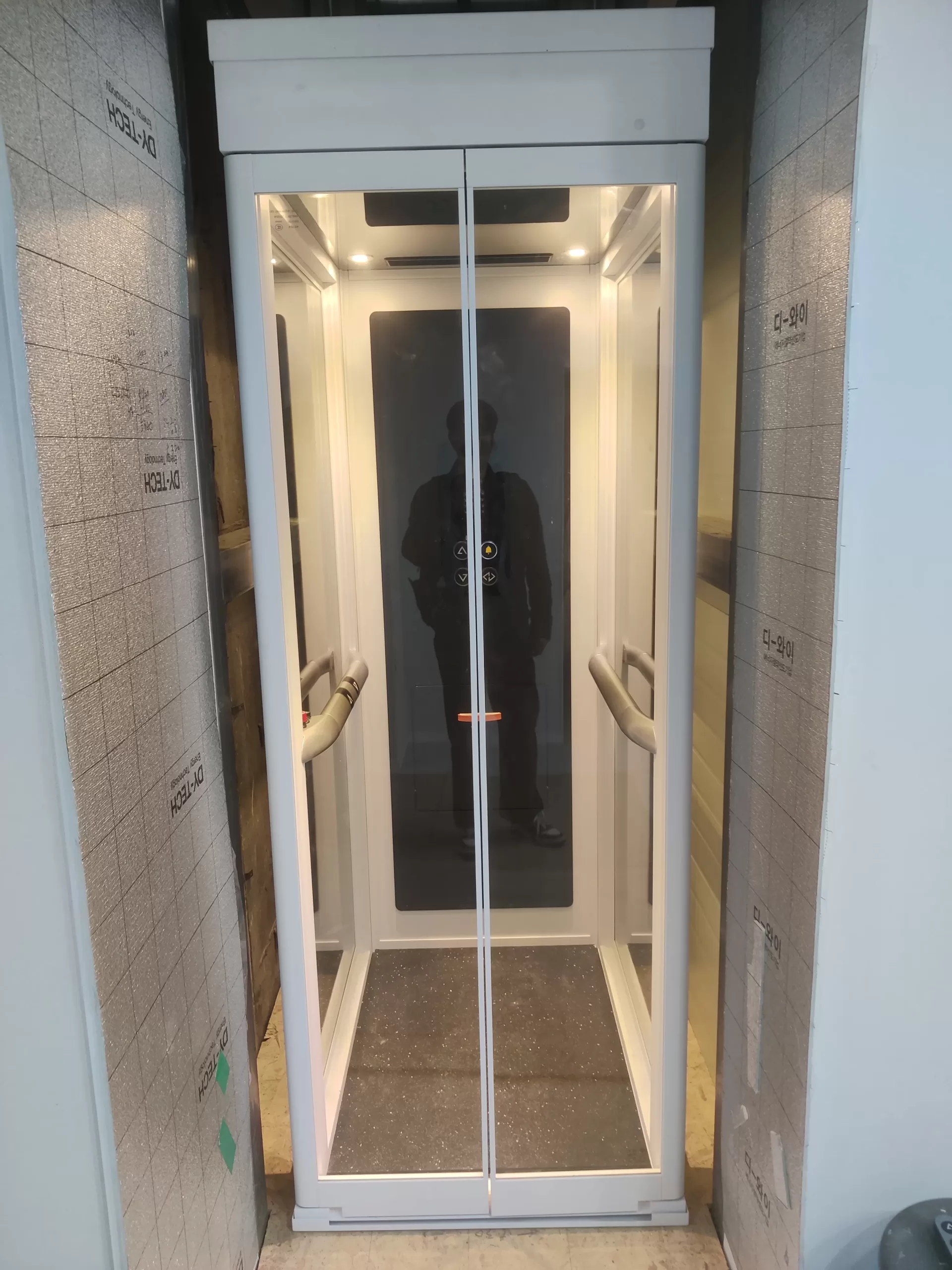Lift rumah Ascenda tipe L terpasang di area koridor, contoh pemasangan rapi dengan kebutuhan ruang terbatas.