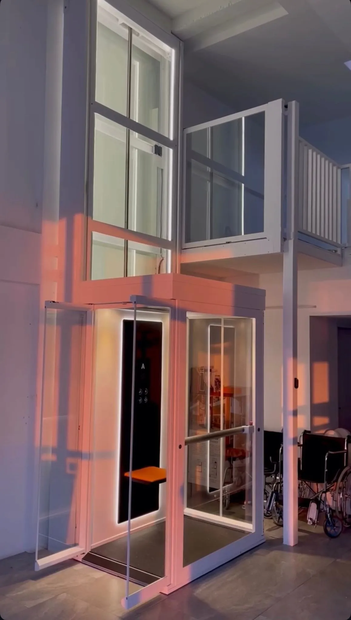 Lift rumah Ascenda putih dengan pintu kaca terbuka di area balkon rumah modern