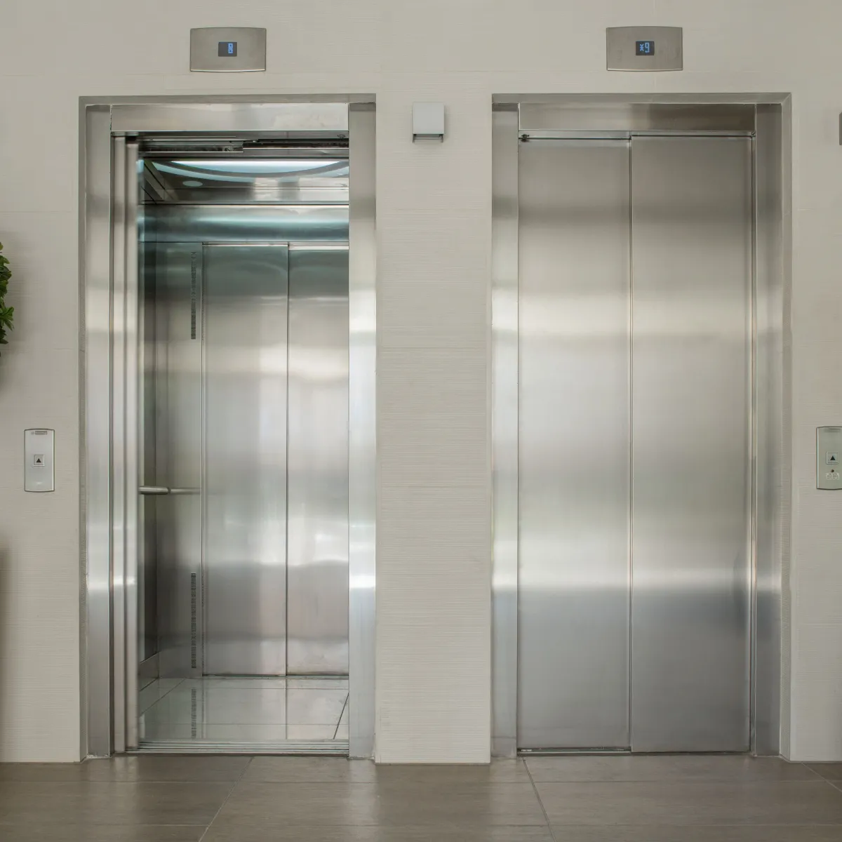 Lift konvensional dengan pintu stainless steel sebagai perbandingan dengan lift rumah screwdrive untuk hunian pribadi.
