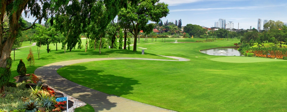 Pondok Indah Golf Course Jakarta Selatan dengan fairway rapi, danau, dan skyline kota di kejauhan.