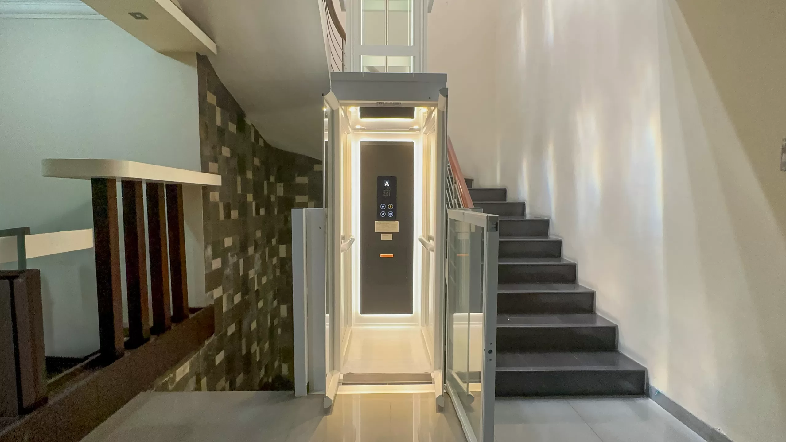 Lift rumah Ascenda Size L terpasang di Medan Area, berdampingan dengan tangga rumah bertingkat modern.