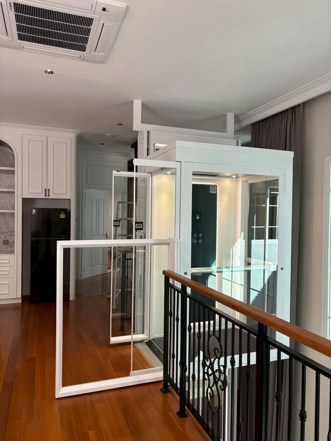 Lift rumah Ascenda terpasang di lantai atas rumah dengan desain kaca dan rangka putih