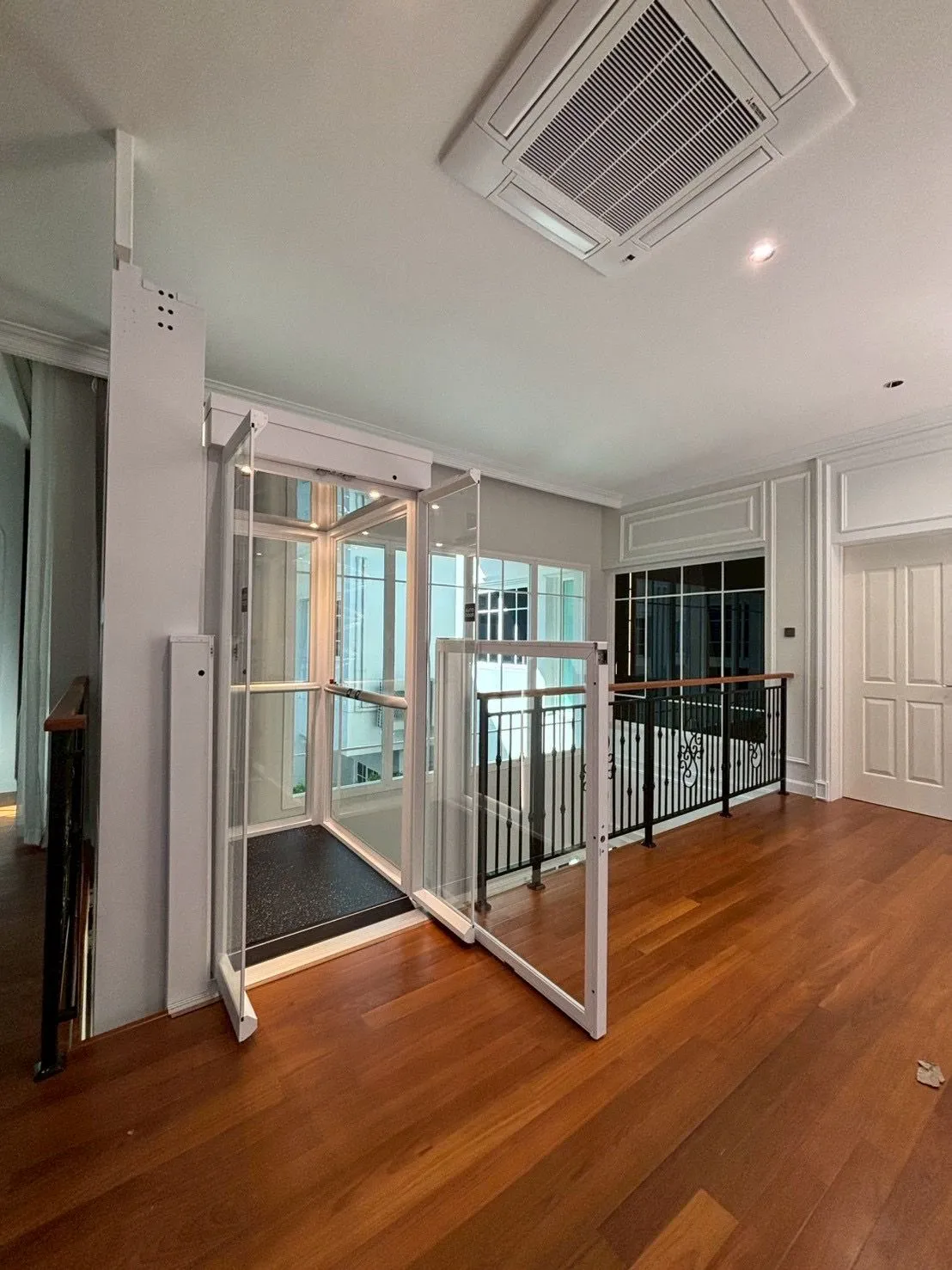 Lift rumah Ascenda di area lantai dua dengan pintu kaca terbuka dan akses dekat railing