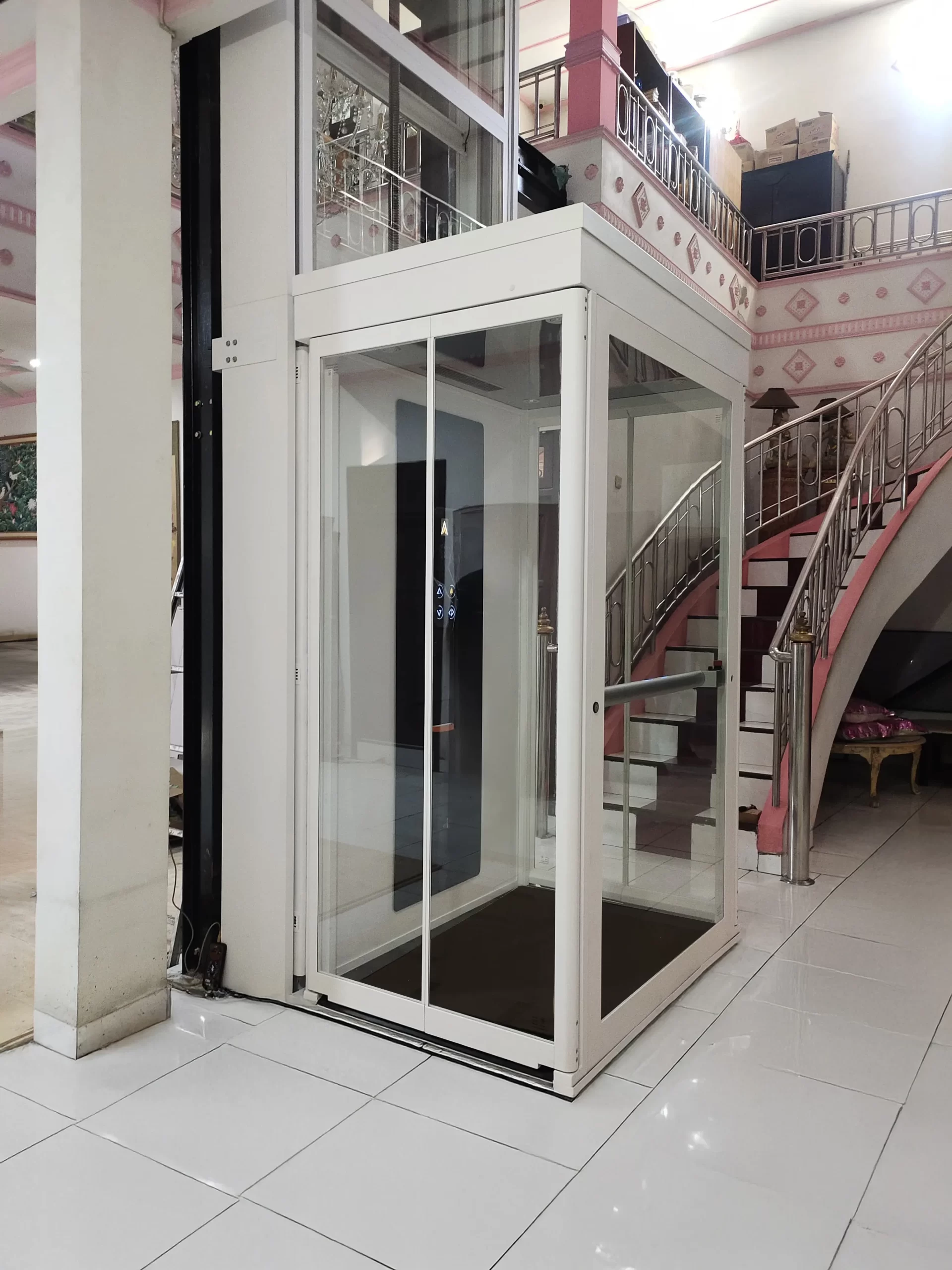 Lift rumah Ascenda by Cibes terpasang di hunian Rungkut, Surabaya Timur, dengan shaft kaca putih dan desain compact dekat area tangga.