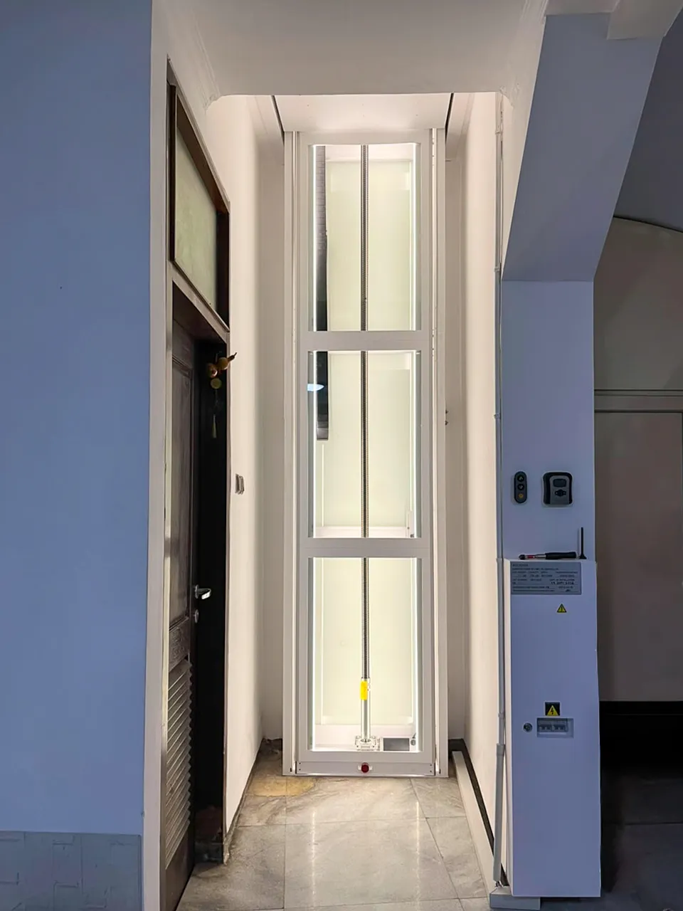 Tampilan shaft lift rumah Ascenda di Tegalsari, Surabaya Pusat, dengan sistem screw drive dan pencahayaan lembut di area rumah.