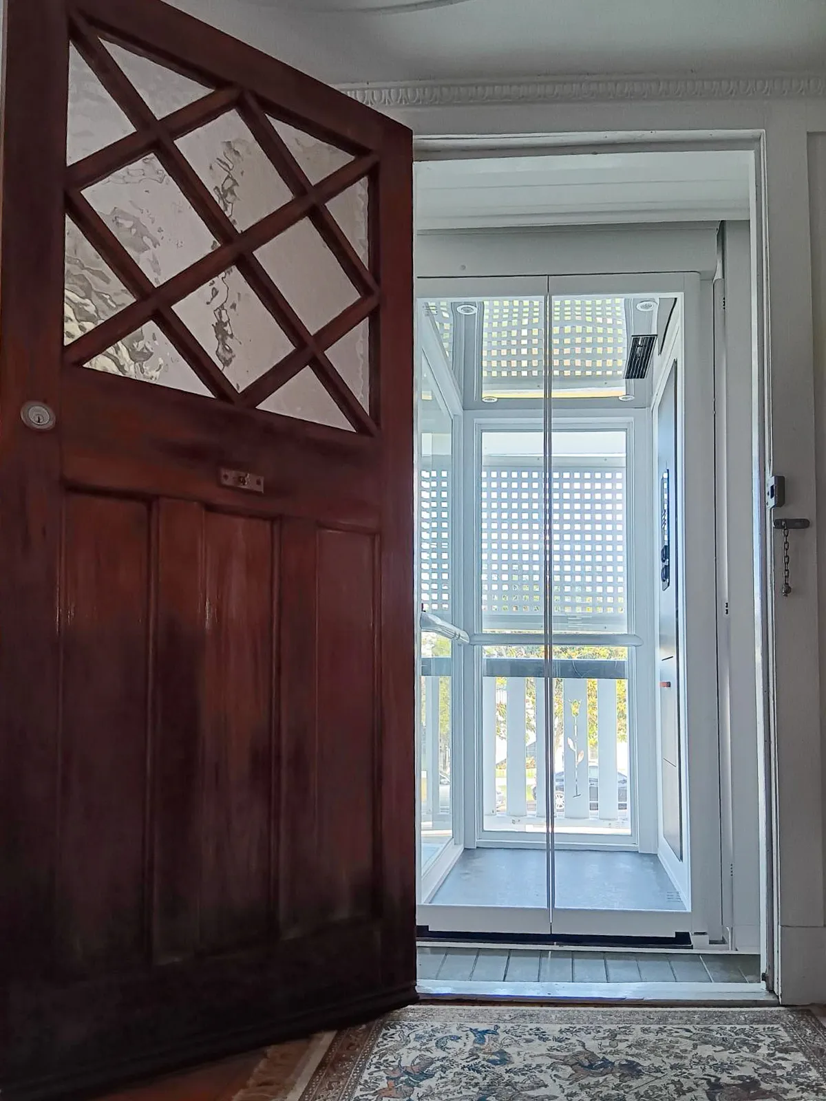 Lift rumah semi-outdoor berwarna putih yang dapat diakses langsung dari dalam rumah melalui pintu utama.