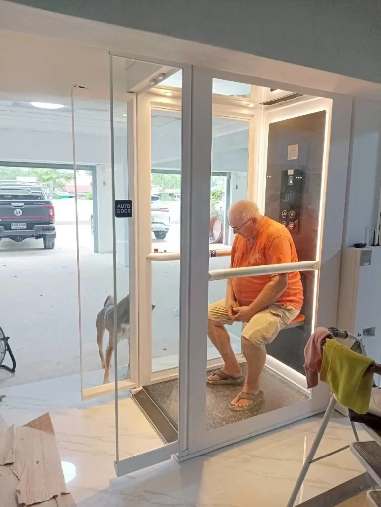 Lansia berada di dalam kabin lift rumah Ascenda bersama anjing peliharaan, menunjukkan penggunaan lift yang nyaman untuk aktivitas harian.