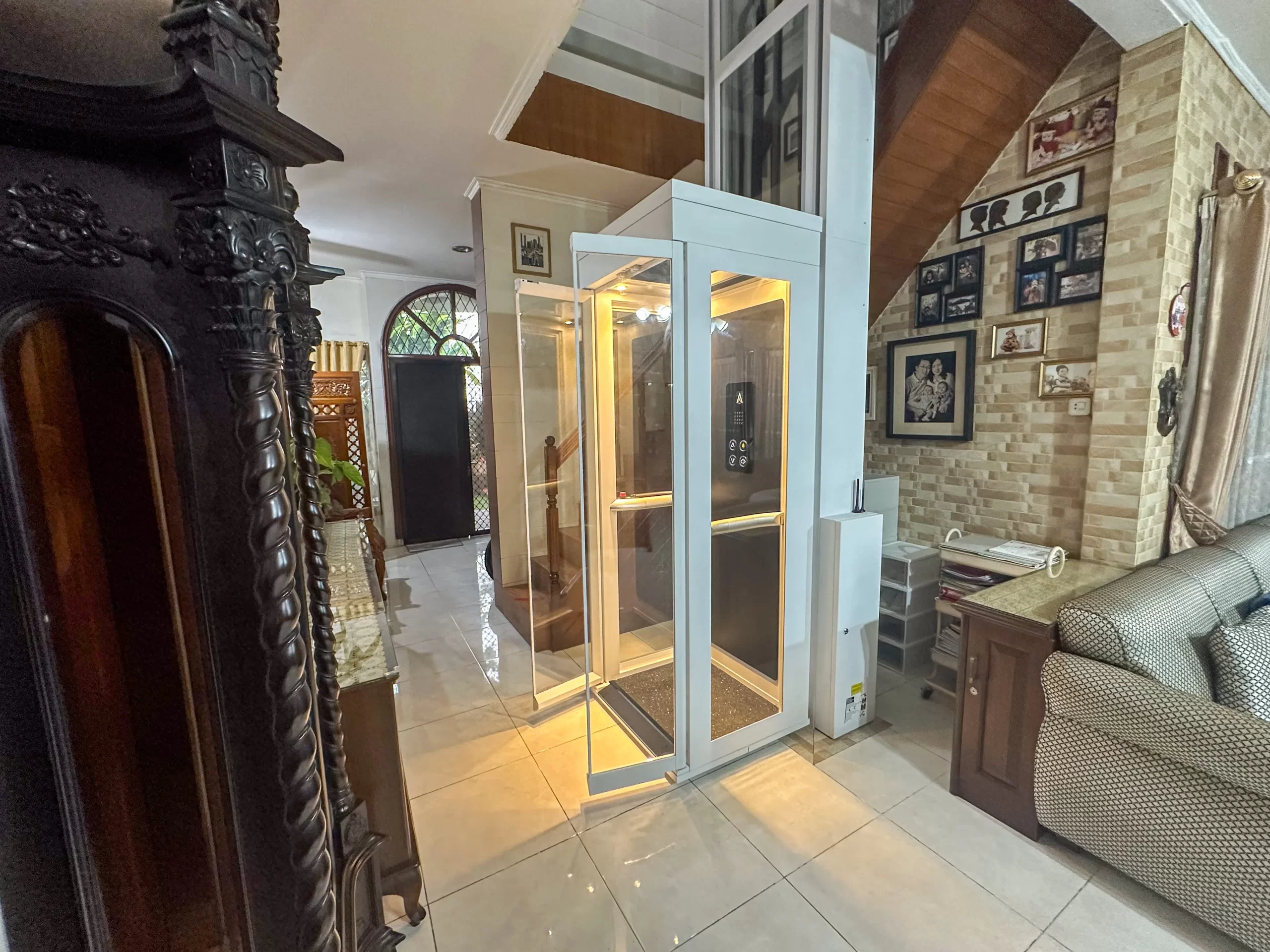Lift rumah kecil Ascenda Size S dengan pintu kaca terbuka di ruang keluarga rumah 2 lantai.